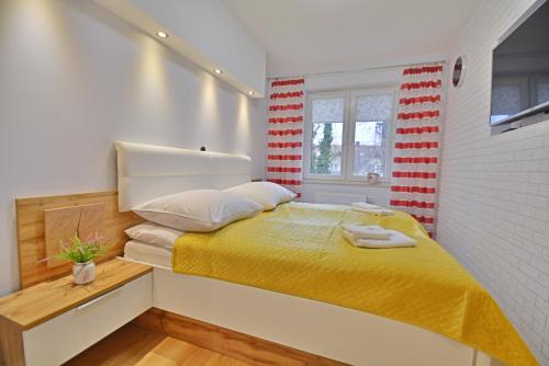a bedroom with a bed with a yellow blanket at Apartamenty Bryza - Ułańska 1B/11 - parking in Świnoujście