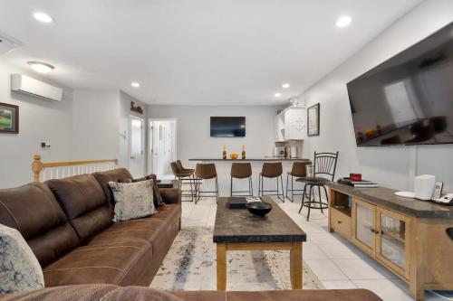 a living room with a brown couch and a kitchen at Heart of Southie - Hot Tub + Walk to Top Bars in Boston