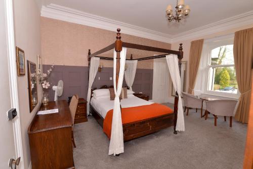 Steeton Hall Hotel & Restaurant في Steeton: غرفة نوم مع سرير المظلة ومكتب