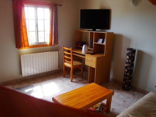 a living room with a desk with a television and a chair at Apart Don Felipe in El Calafate
