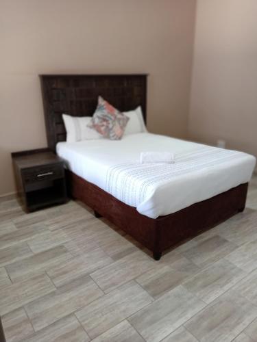 a bedroom with a bed and a wooden floor at AMANI PALMS GUEST HOUSE in Klerksdorp