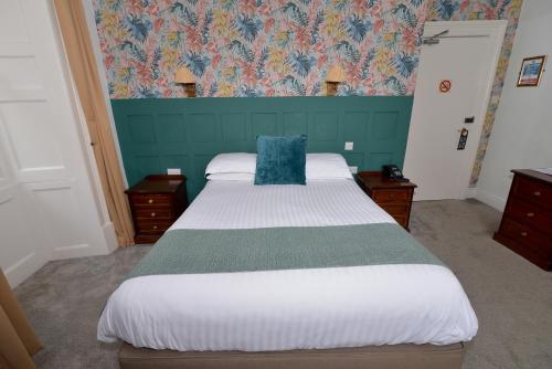 a bedroom with a large bed with a blue headboard at Steeton Hall Hotel & Restaurant in Steeton