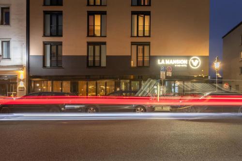 a car driving down a street in front of a building at La Mansion Vi Vadi Hotel in Munich
