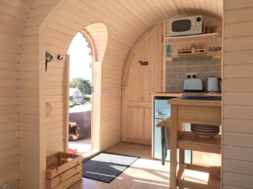 a kitchen with an archway in a tiny house at The Pasty - Lydcott Glamping in East Looe