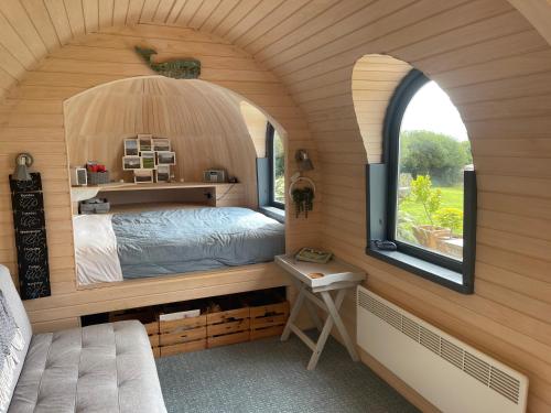 a bedroom in a tiny house with an arched window at The Pasty - Lydcott Glamping in East Looe