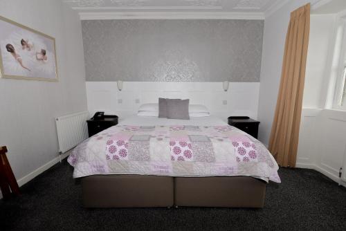 a bedroom with a bed with a pink and white comforter at Steeton Hall Hotel & Restaurant in Steeton