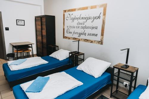 two beds in a room with a sign on the wall at Noclegi Bielpon in Przemyśl