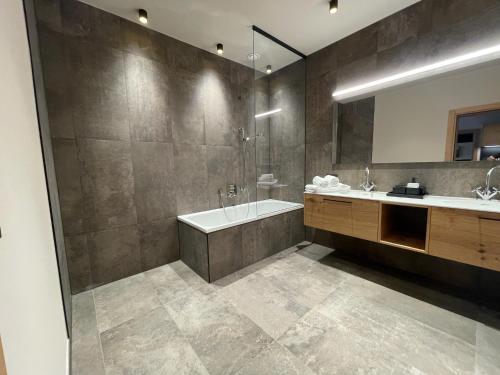a bathroom with a tub and a sink and a mirror at Heimat 1495m Appartement TYP 8 in Schröcken