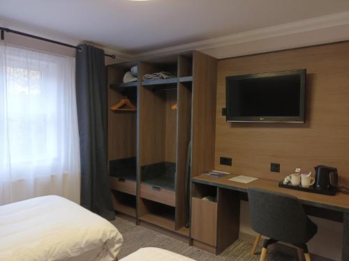 a hotel room with a bed and a desk with a television at Corn Mill Lodge Hotel in Leeds