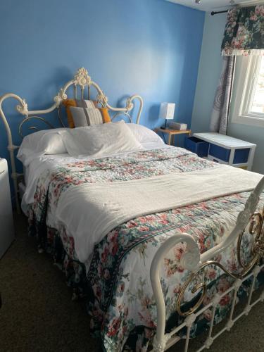 Dormitorio azul con cama con colcha de flores en Comfortable stay en Milton