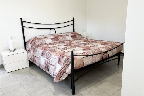 a bed in a white room with a black frame at Le 4 Stagioni in Comacchio