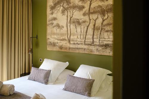 a bed with two pillows and a painting on the wall at Le Répertoire - La Villa des 2 Soeurs in Pernes-les-Fontaines