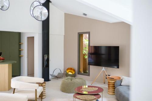 a living room with a couch and a tv at Le Répertoire - La Villa des 2 Soeurs in Pernes-les-Fontaines