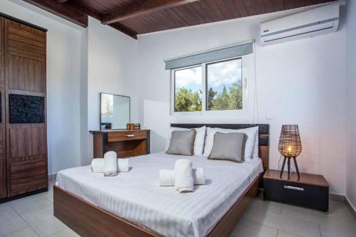a bedroom with a large white bed with a window at Kalimera Villa By the Sea in Gennadi