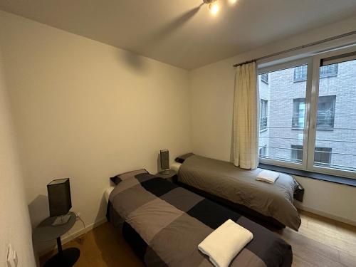 een slaapkamer met 2 bedden en een raam bij Lichtrijk mooi appartement met zicht op hof van Roosendael in Antwerpen
