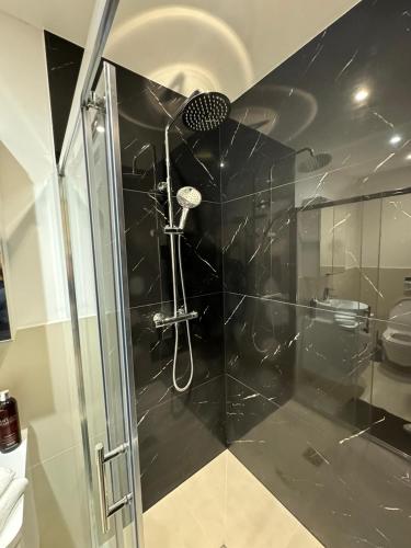 een douche met een glazen deur in de badkamer bij Modern 1BD Flat in Londen