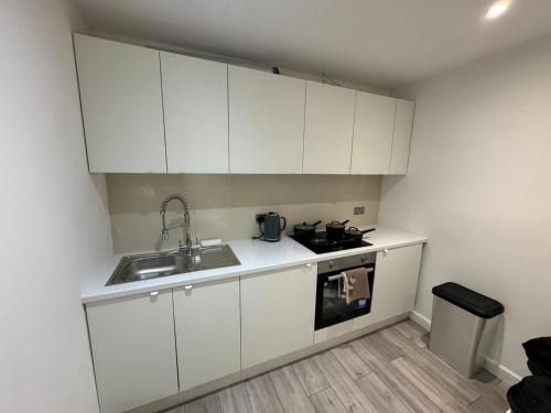 a small kitchen with white cabinets and a sink at Modern 1BD Flat in London