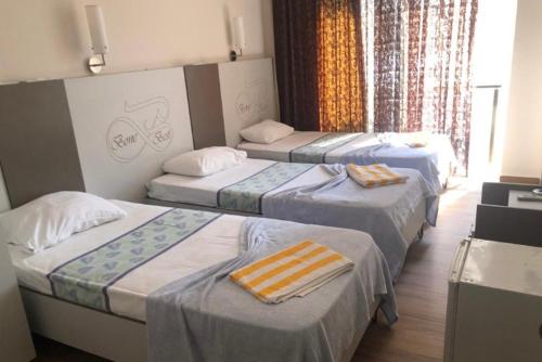 a hotel room with three beds with towels on them at BONE BEST OTEL in Antalya