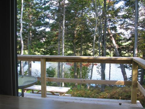 a porch with a bench and a table and trees at Millstream Cottages in Brackley Beach