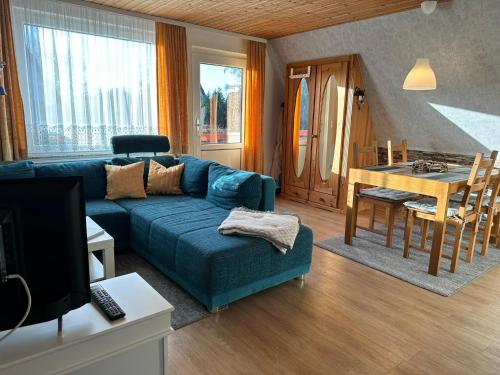 a living room with a blue couch and a table at Finnhütte 7 Mönchgut in Lobbe