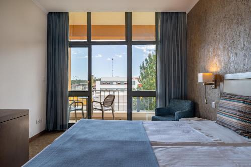 a hotel room with a bed and a large window at VILA PARK Nature & Business Hotel in Santo André