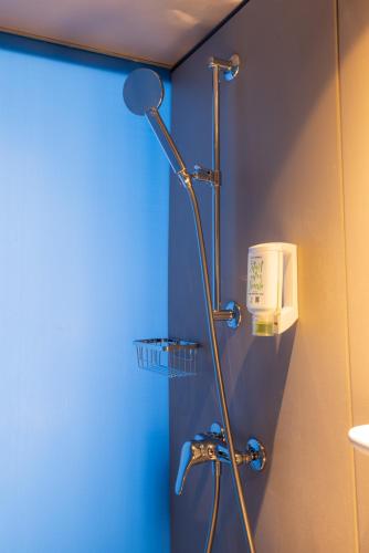 a shower in a bathroom with a blue wall at Fred Guest House Hauptbahnhof - Mobile Check-in in Zürich