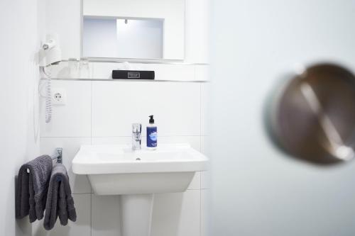 uma casa de banho branca com um lavatório e um espelho em Vareler Brauhaus-Hotel em Varel