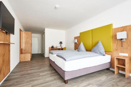 um quarto com uma cama grande e uma televisão de ecrã plano em Vareler Brauhaus-Hotel em Varel