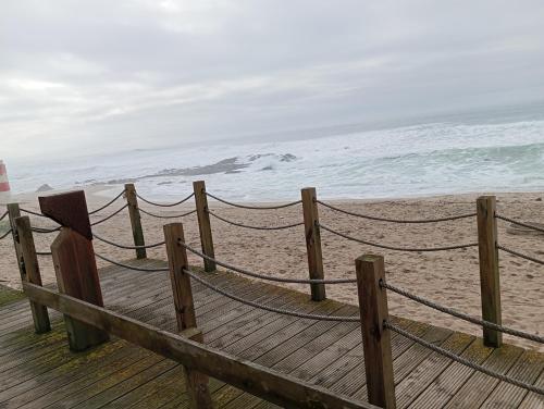 a wooden pier with a hammock on the beach at LOFT Aver-o-mar 2 min a pé da praia in Póvoa de Varzim