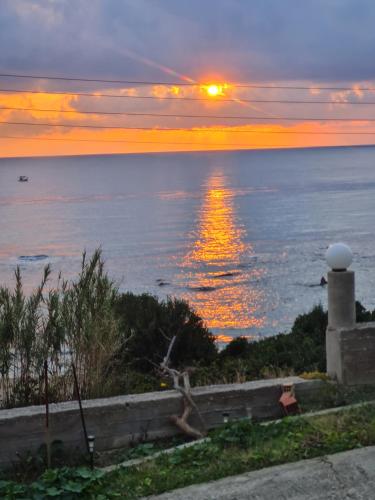 a sunset over the ocean with a lighthouse at VILLA VRACHOS Preveza in Vráchos
