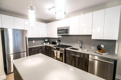 una cocina con armarios blancos y electrodomésticos de acero inoxidable en Modern Apart Downtown with Indoor Pool, en Stamford