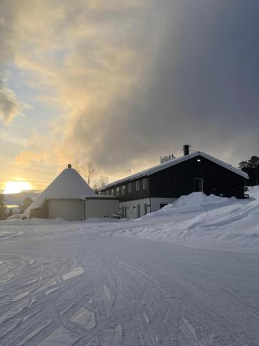 a barn in the snow with a building at SamiCity Hotel As in Karasjok