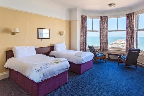 um quarto de hotel com duas camas e uma mesa e cadeiras em Hotel De Paris em Cromer