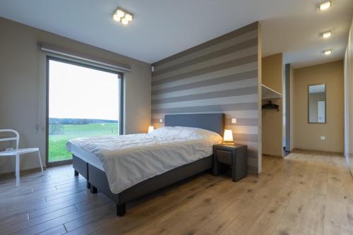 um quarto com uma cama grande e uma janela grande em Villa Aquatenne em Tenneville