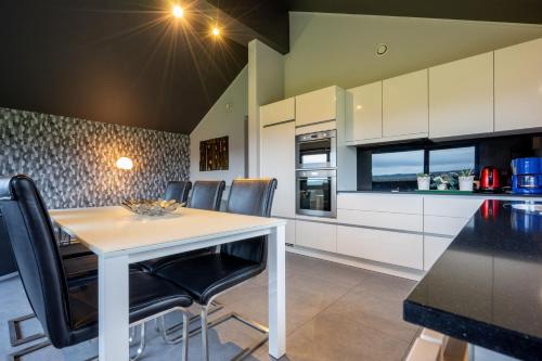 a kitchen with a white table and black chairs at Villa Aquatenne in Tenneville