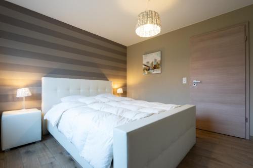 a bedroom with a large white bed and a lamp at Villa Aquatenne in Tenneville
