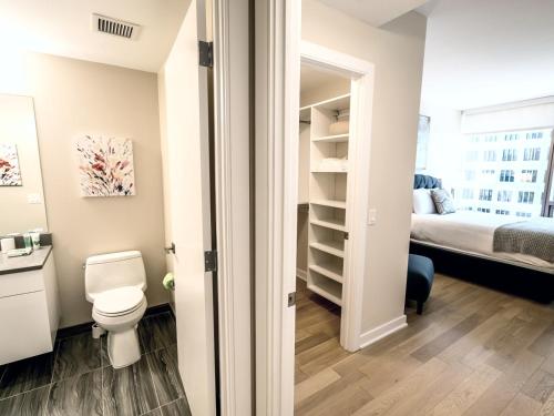 a bathroom with a toilet and a bedroom at Spacious Apt Downtown with Gym in Stamford