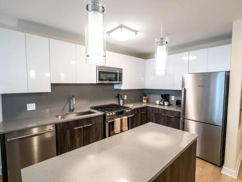 a kitchen with white cabinets and a stainless steel refrigerator at Spacious Apt Downtown with Gym in Stamford