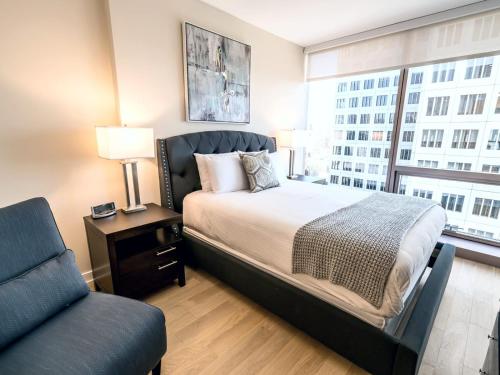 a bedroom with a bed and a chair and a window at Spacious Apt Downtown with Gym in Stamford