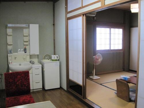 a bathroom with a sink and a refrigerator and a mirror at Suminoe Ryokan in Onomichi