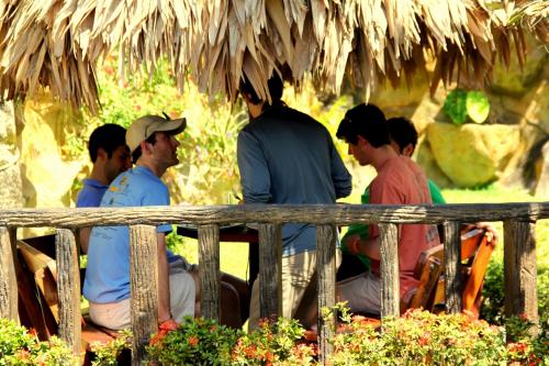 a group of people sitting on a bench under a hut at Poshtel Arenal in Fortuna