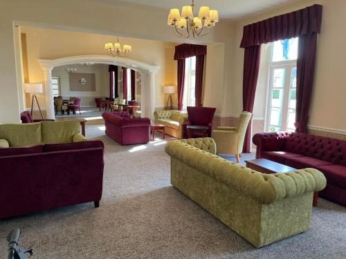 ein Wohnzimmer mit Sofas, Stühlen und einem Spiegel in der Unterkunft Royal Norfolk Hotel in Bognor Regis