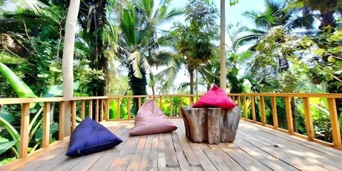 three colorful pillows sitting on a wooden deck at Lumbung Langit Bali house & hostel in Tampaksiring