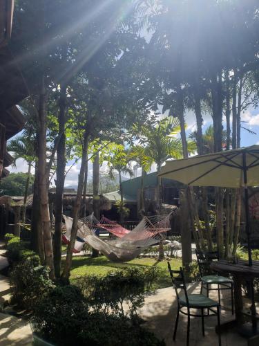 a hammock in a garden with trees and chairs at Poshtel Arenal in Fortuna