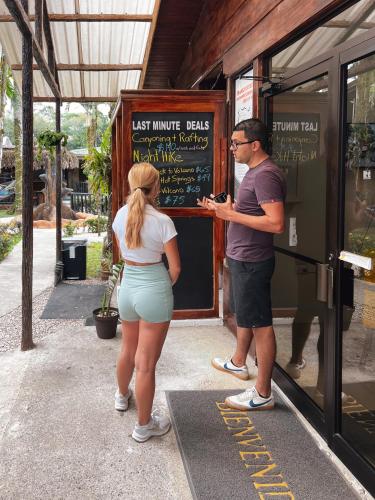 a man and a woman standing in front of a menu at Poshtel Arenal in Fortuna