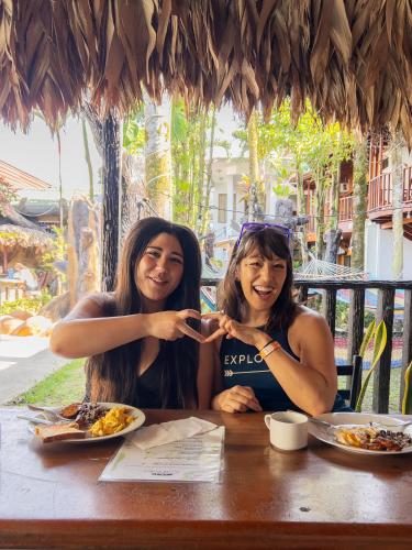 two women sitting at a table eating food at Poshtel Arenal in Fortuna