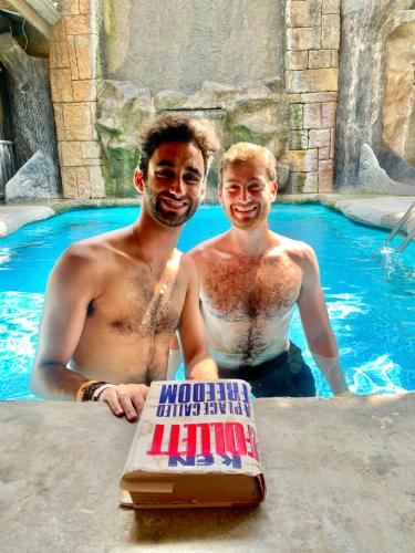 two men standing in a swimming pool with a birthday cake at Poshtel Arenal in Fortuna