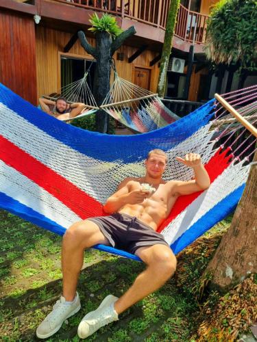 a man laying on a hammock with a bottle of wine at Poshtel Arenal in Fortuna