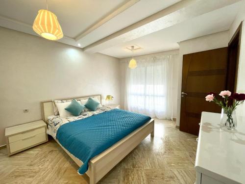 Schlafzimmer mit einem Bett mit blauer Bettwäsche und einem Fenster in der Unterkunft Appartement Tanger Moulay Ismail in Tangier