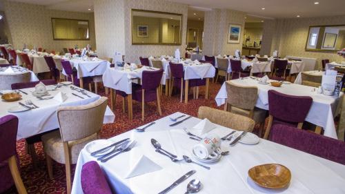 un comedor con mesas blancas y sillas moradas en New Beach Hotel, en Great Yarmouth